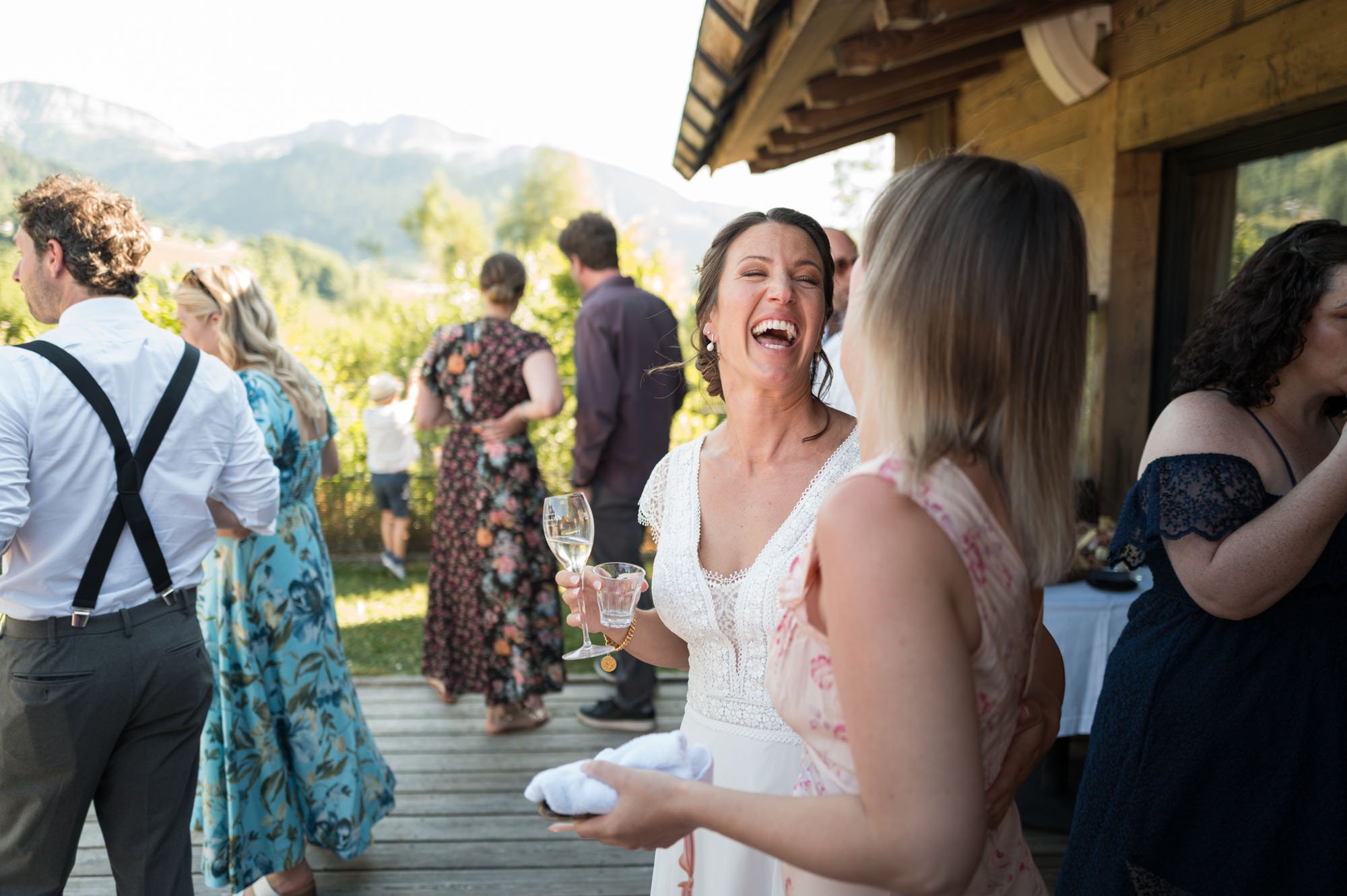 Groupe de personnes souriantes qui pétillent, profitant d'une fête en extérieur, avec un décor montagneux en arrière-plan.