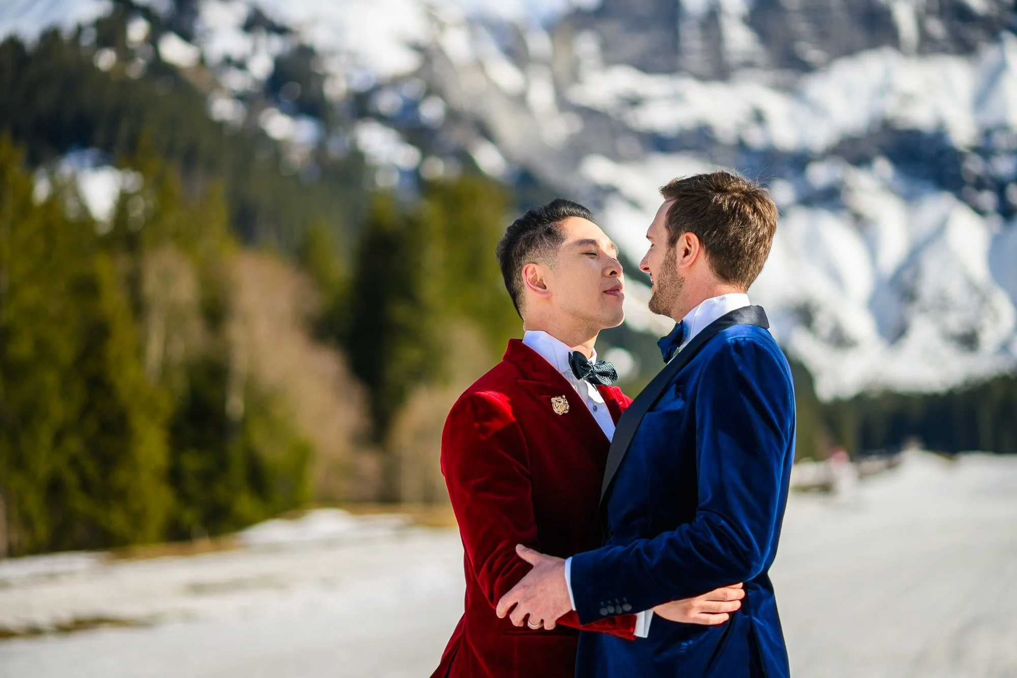 Deux hommes habillés en costumes de mariée dans un paysage enneigé embrassent tendrement.