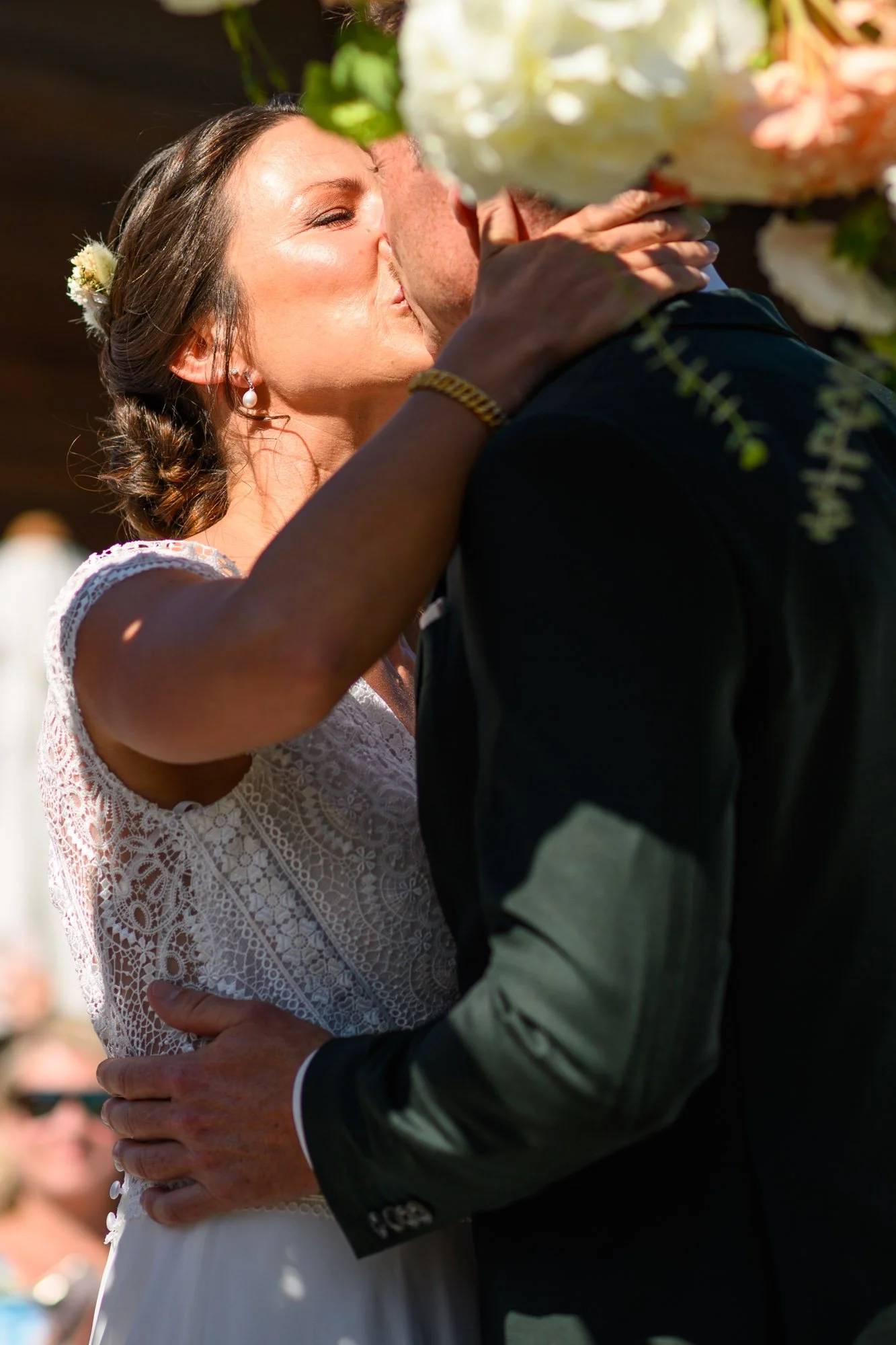 Un couple en robe de mariage et costume en train de s'embrasser lors d'une cérémonie de mariage en plein air