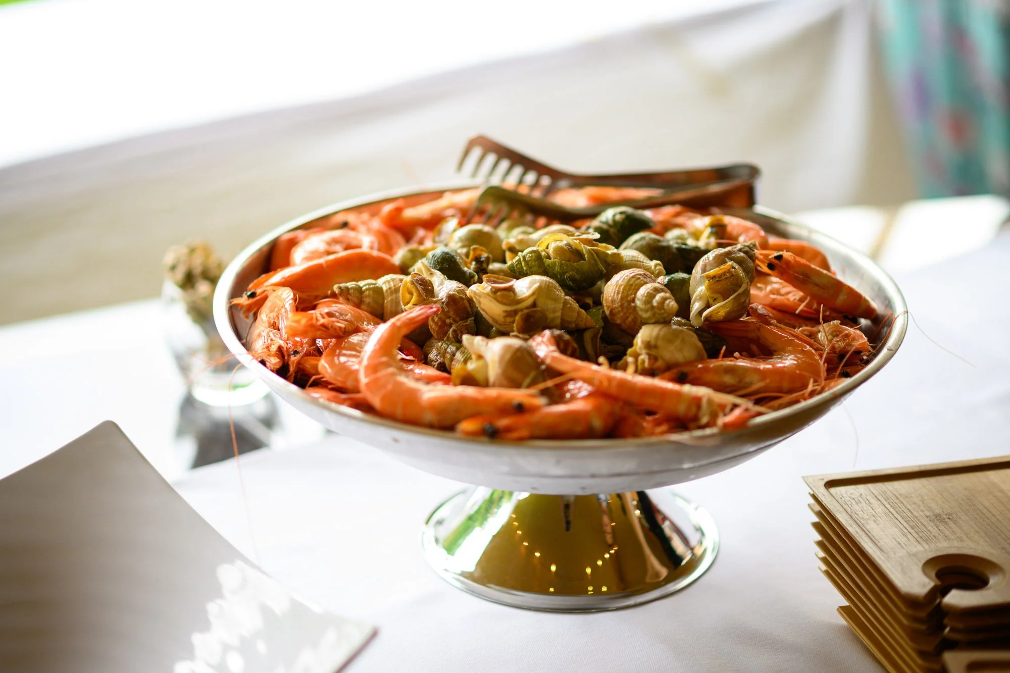 Plate d'crustacés, comprenant des crevettes roses et des coquillages, sur une table.