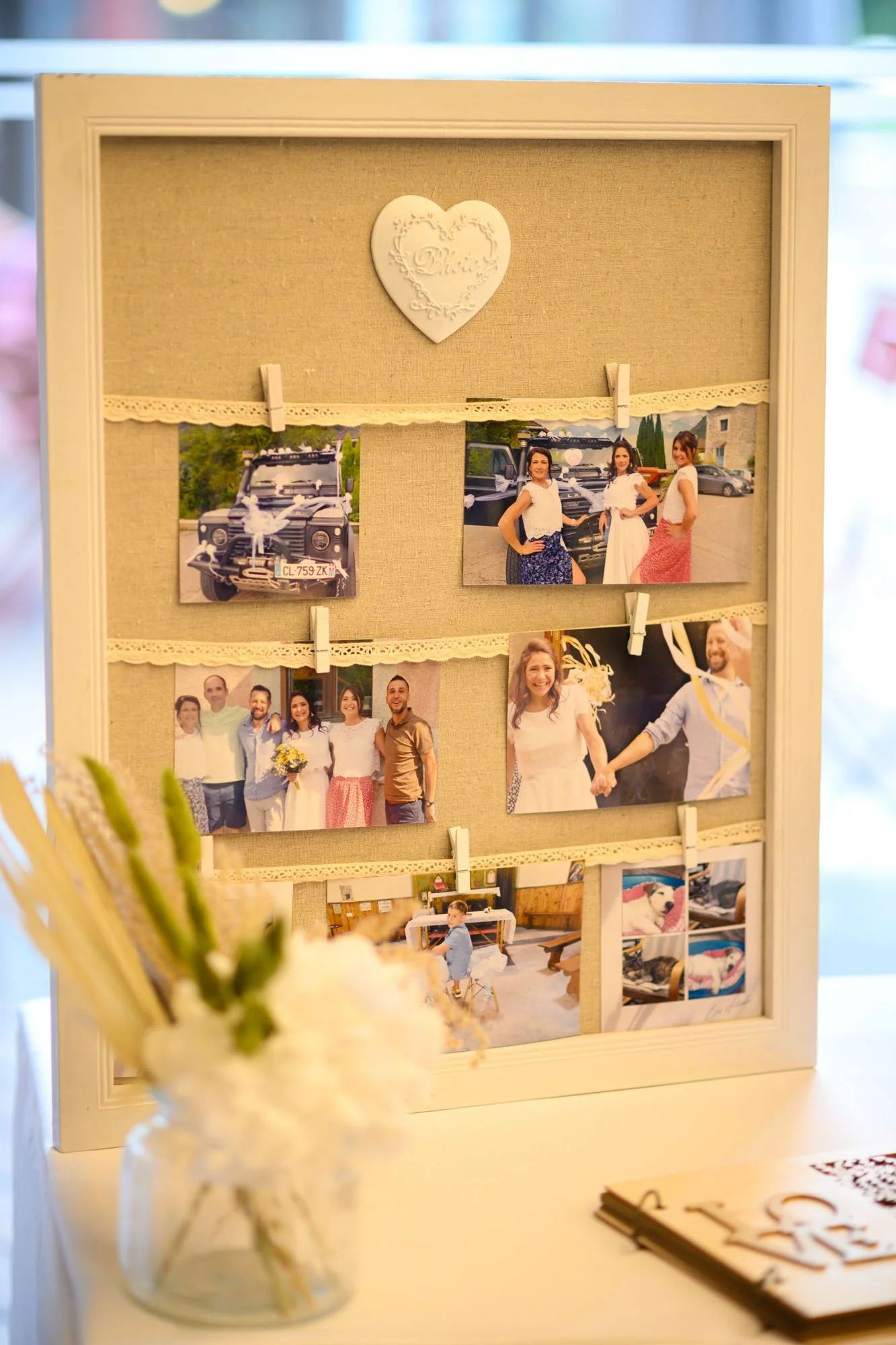 Pêle-mêle photo avec plusieurs photos de groupe et d'événements, décoré avec un cœur en haut et des pinces à linge, dans un cadre blanc, probablement pour une occasion spéciale.