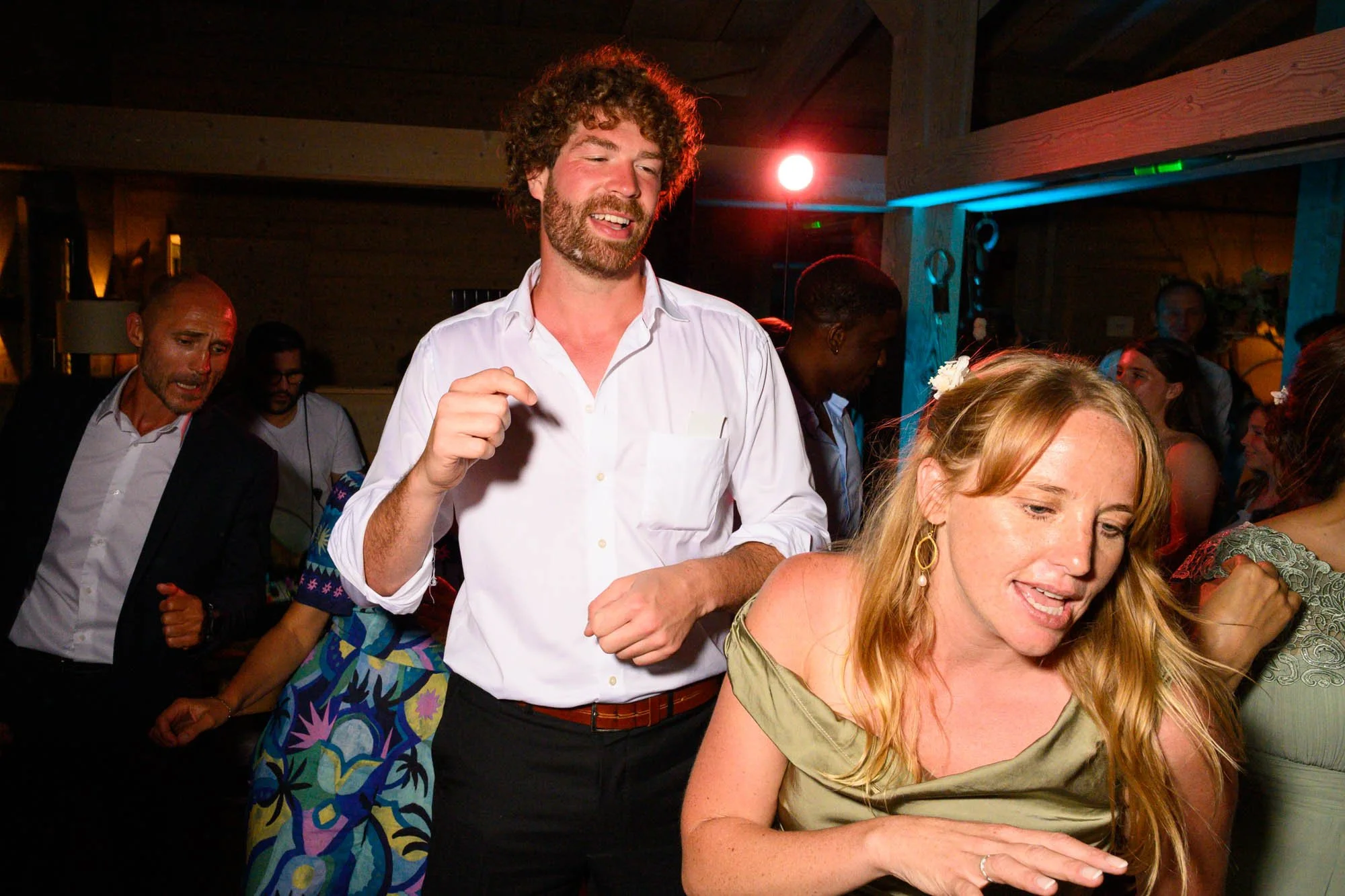 Groupe de personnes dansant lors d'une fête, avec un éclairage coloré et une ambiance festive.