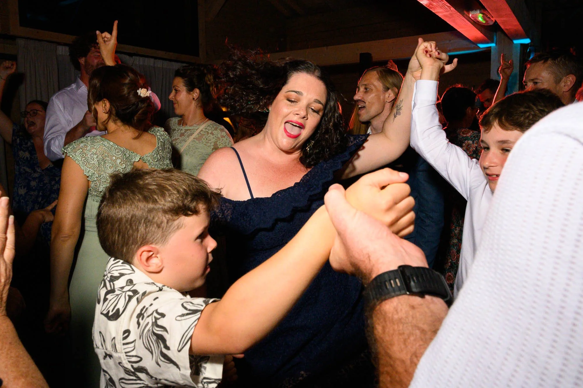 Groupe de personnes dansant et s'amusant lors d'une fête, souriants et en mouvement, dans une ambiance joyeuse.