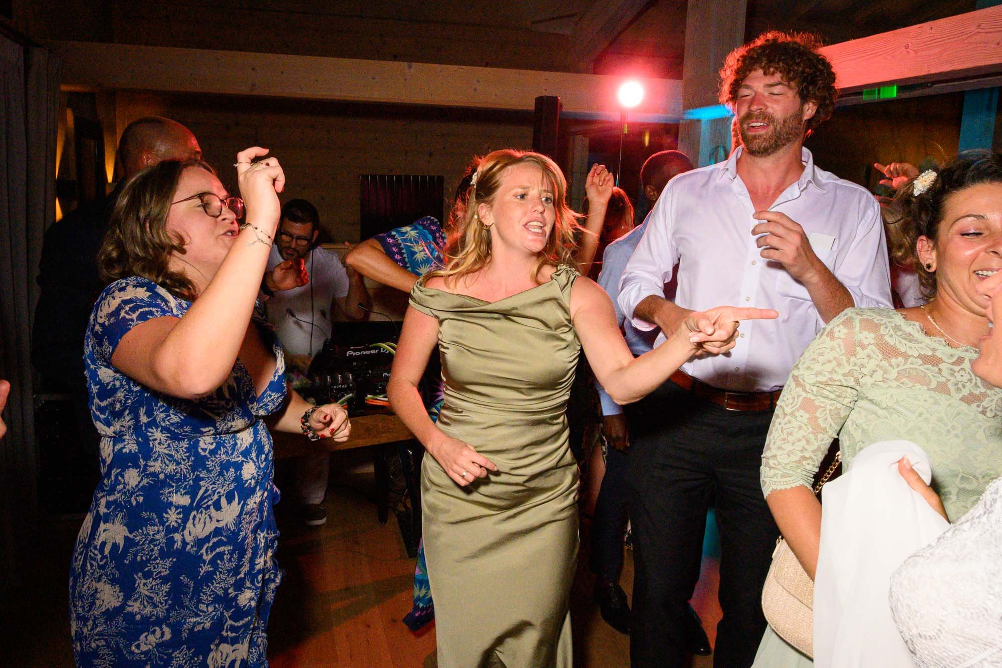 Groupe de personnes dansant et s'amusant lors d'une fête ou d'un mariage, ambiance festive avec éclairage coloré.