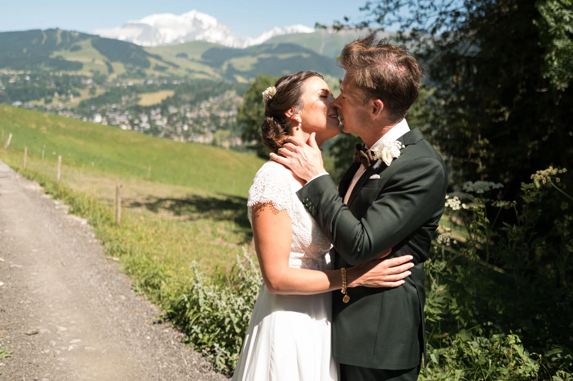Un couple de mariés s'embrassant dans un paysage de montagne ensoleillé.