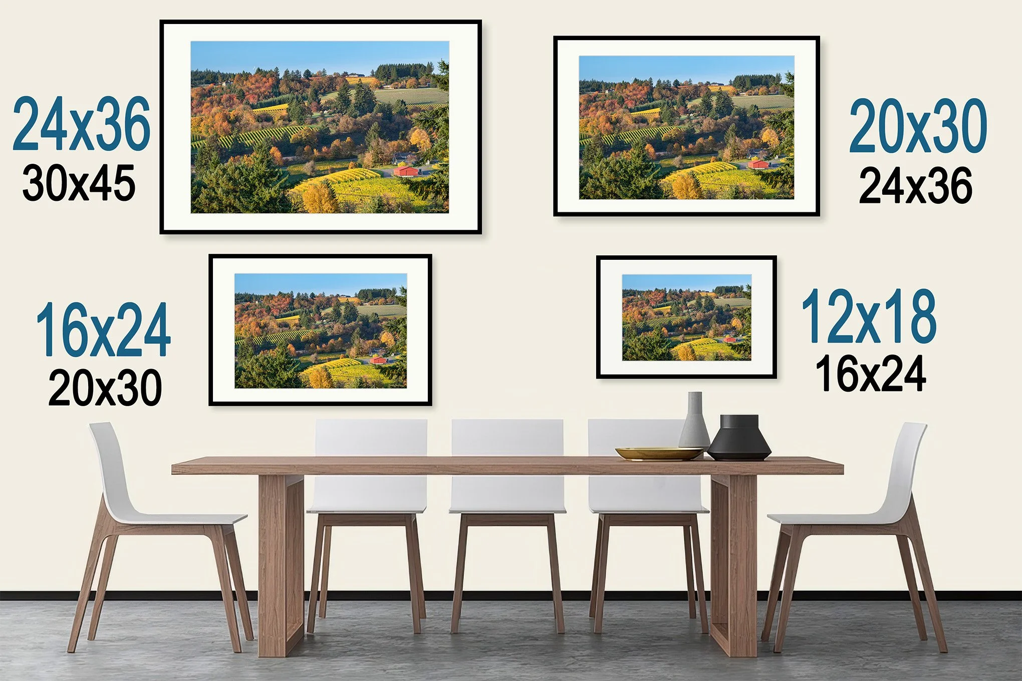 A dining room with a wooden table and five white chairs. The wall behind has four framed landscape photographs with size labels indicating their dimensions.