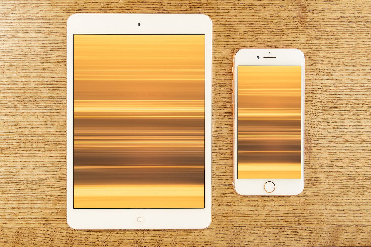 Tablet and smartphone placed side by side on a wooden surface, each displaying a Stripes digital wallpaper, an abstract image composed of horizontal bands of warm gold and brown colors.
