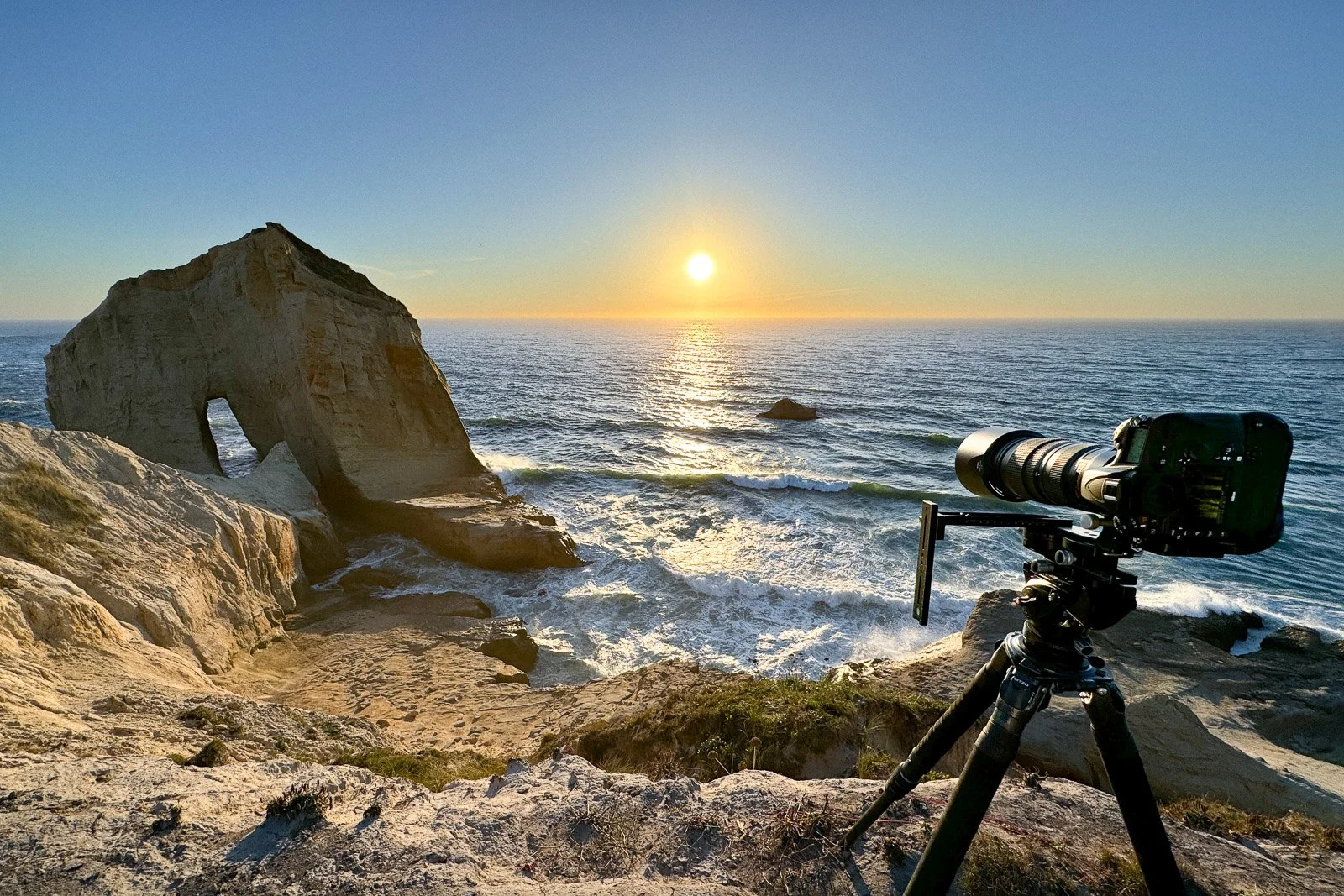 On-location photograph at Cape Kiwanda on the Oregon Coast, showing artist Brendan Alex Phoenix photographing sunlight on the ocean to create original BAPstracts — abstract ocean photography visualizing time and the fabric of spacetime.