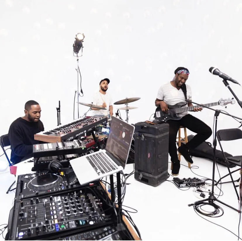 Keyboardist, drummer and bassist recording in a white studio