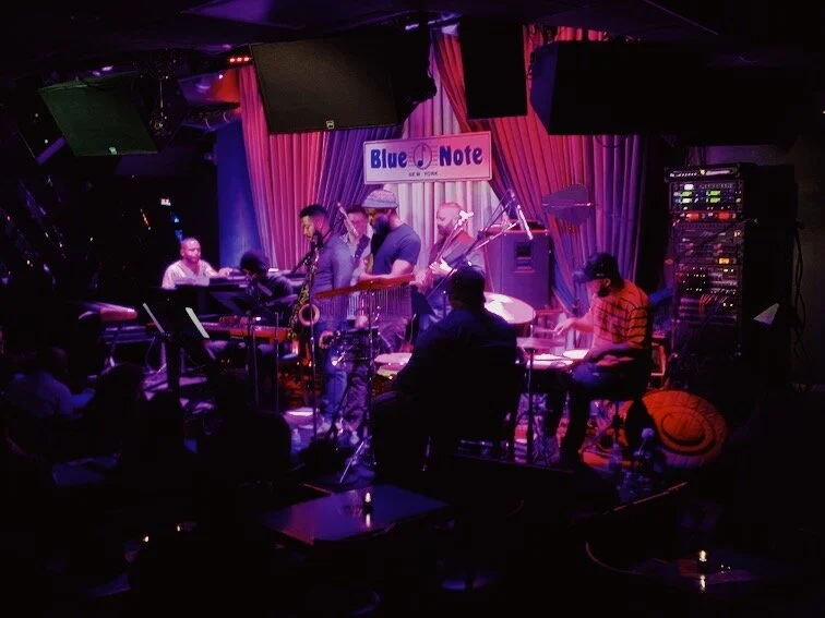 Ensemble performing on a purple-lit Blue Note stage