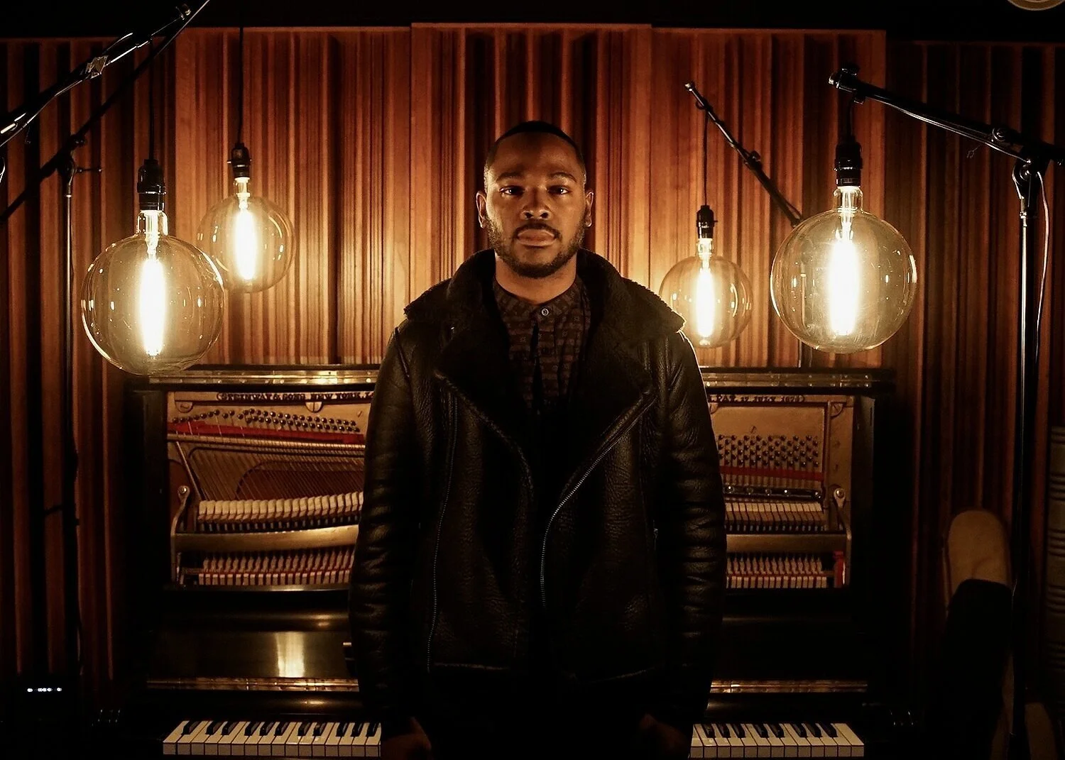 Portrait in front of an open upright piano and warm hanging lights