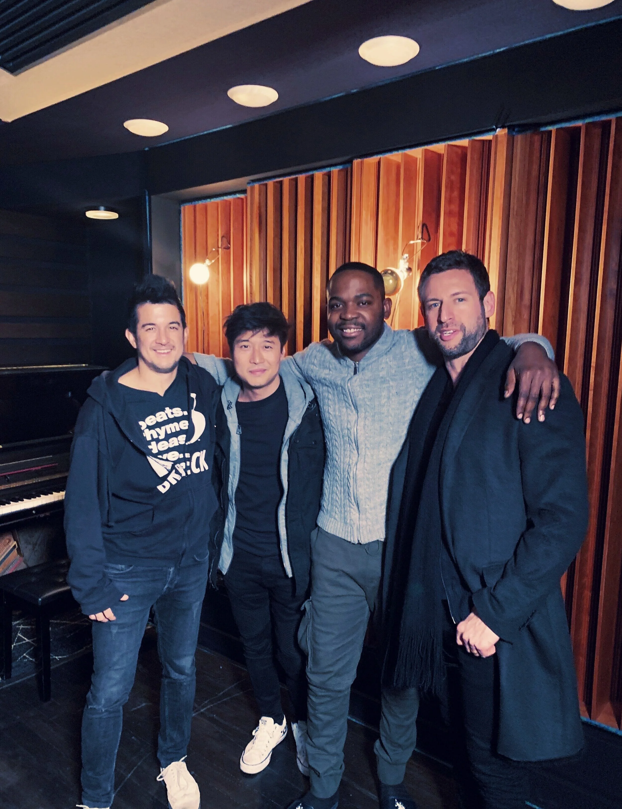 Four people posing together in a recording studio