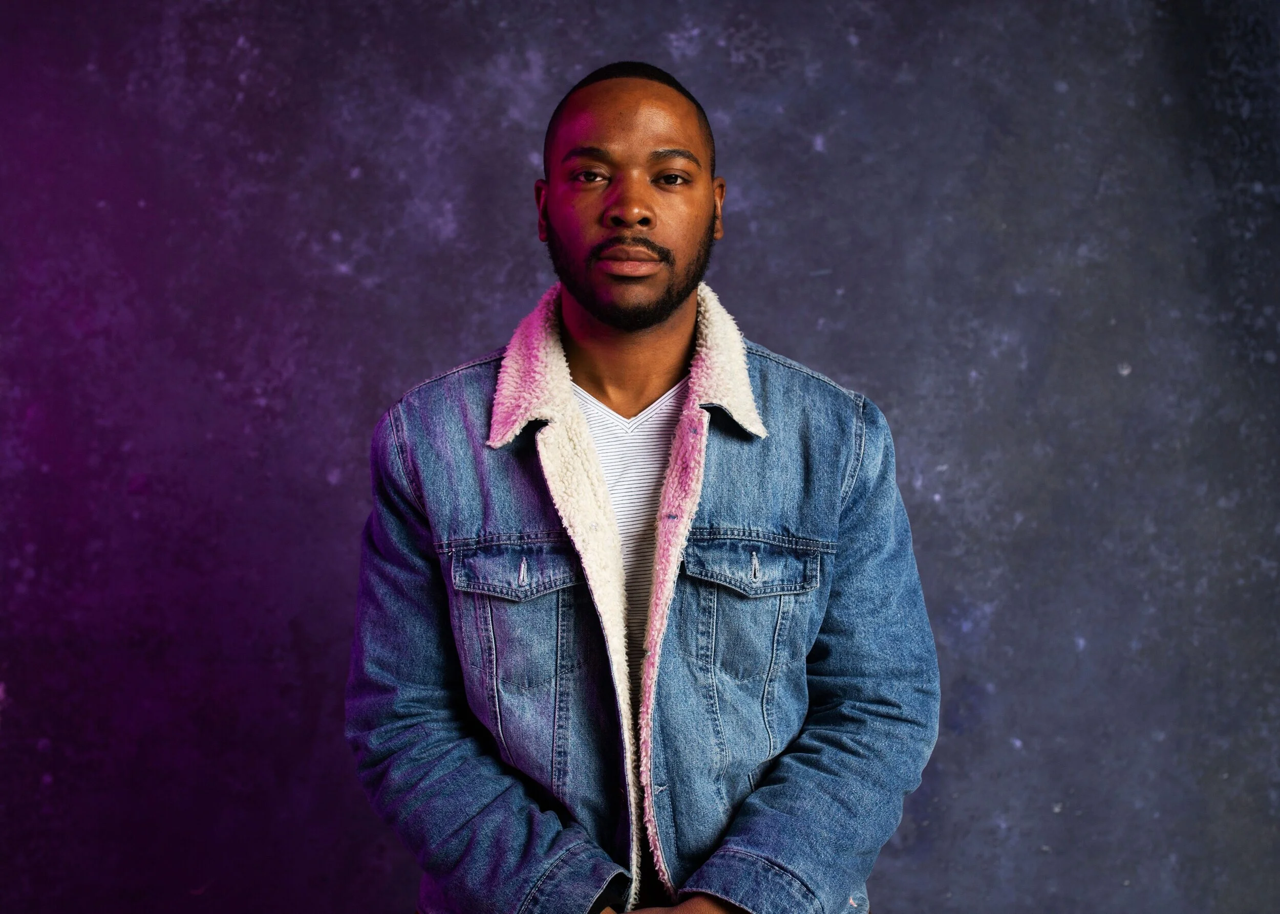 Portrait in a denim jacket against a purple-blue backdrop
