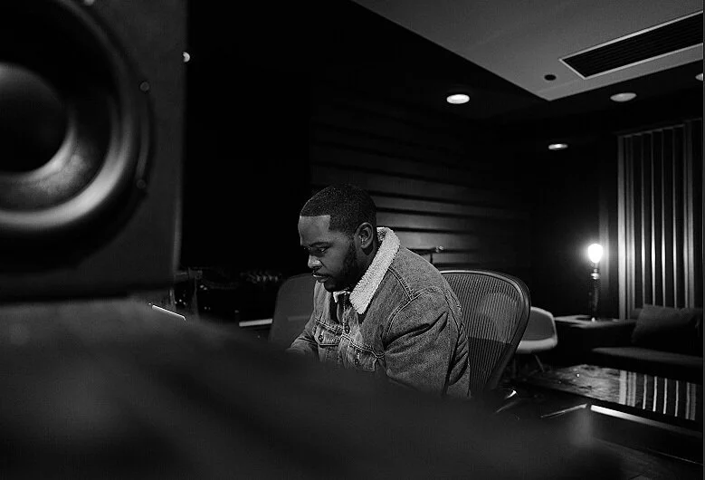Black-and-white pianist in a studio, framed beyond a speaker