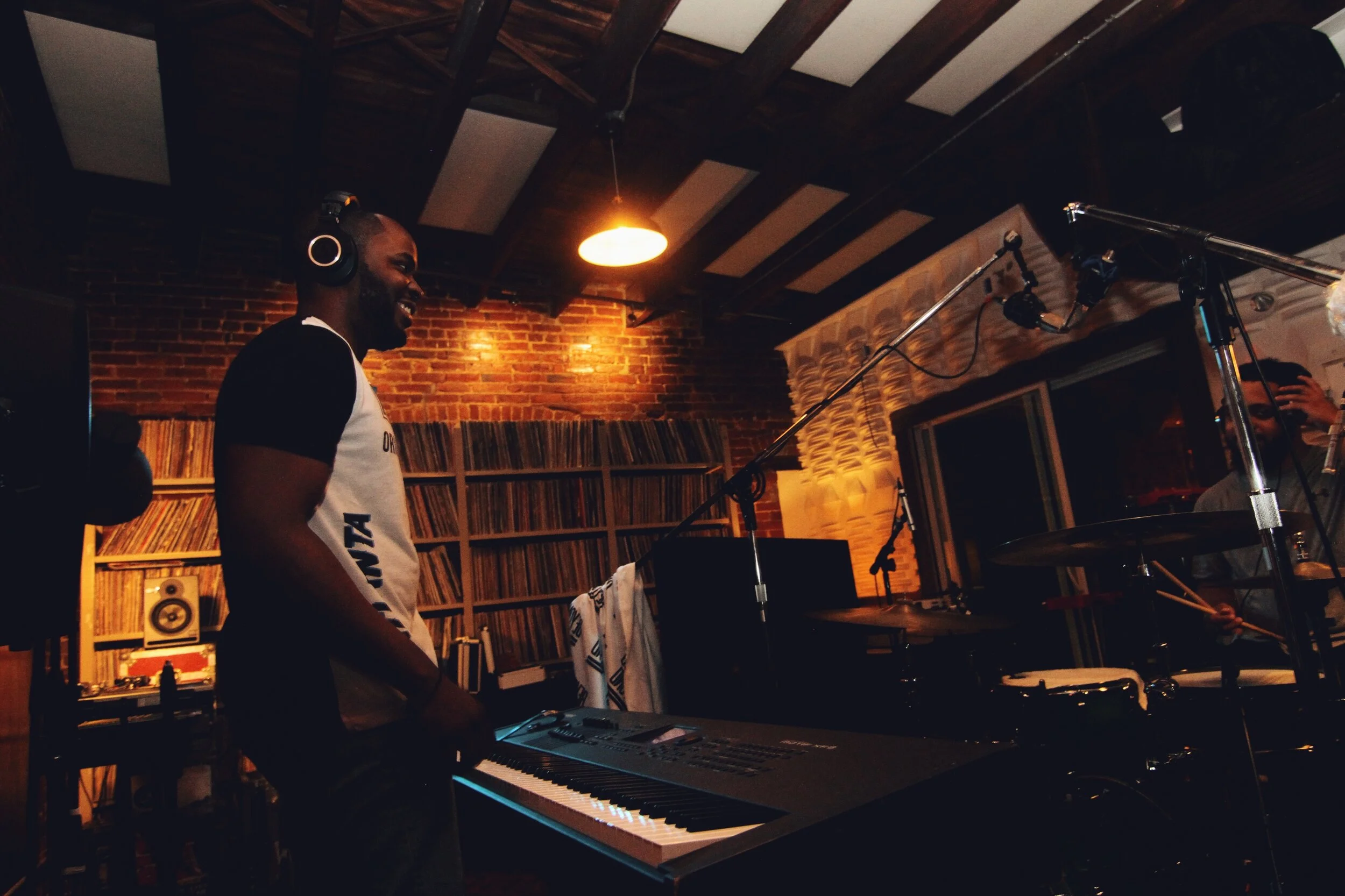 Wide view of a keyboard player in a warmly lit recording studio