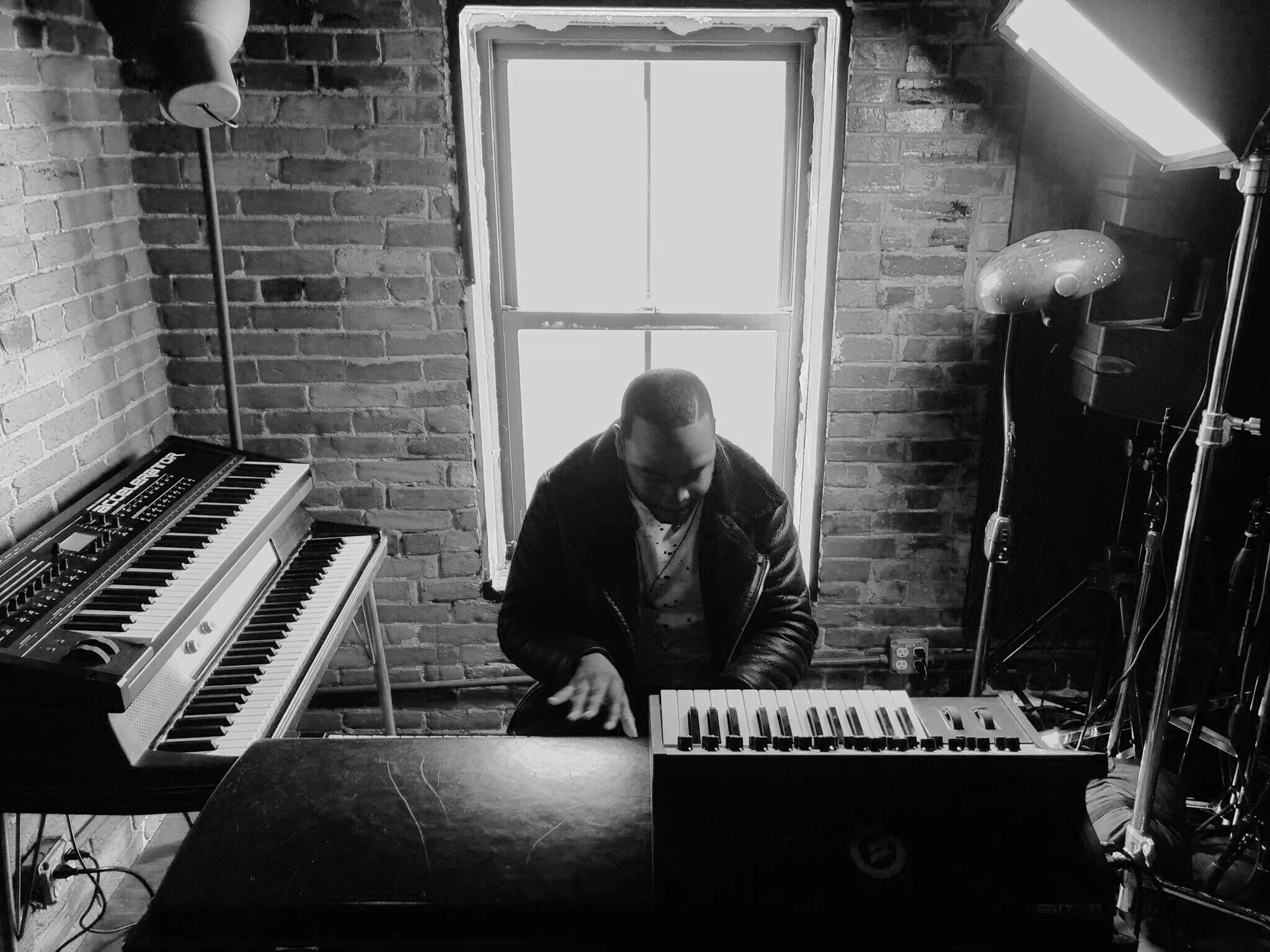 Black-and-white overhead view of a pianist surrounded by keyboards