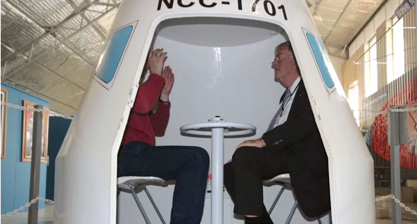 WA Governor Kim Beazley (right) goes for a spin in a space capsule at the Gravity Discovery Centre