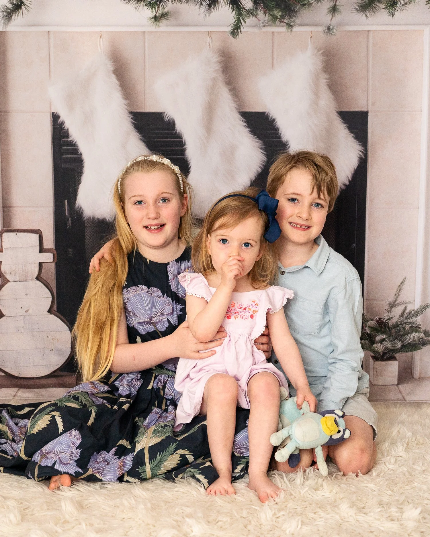 Photo of two girls and a pug dog dressed in red with a Christmas backdrop