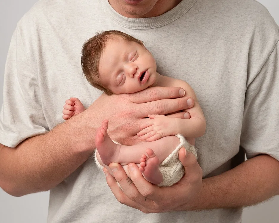 newborn baby sleeping held in her father's hands on his chest shot by Melbourne newborn photogapher