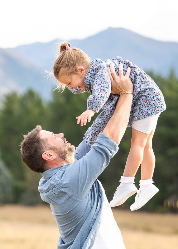 Dad throwing his daughter up above him and they are smiling at each other