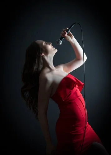 Branding image by Susan Bradfield Photography of a female singer in a red dress singing into the microphone with her back arched