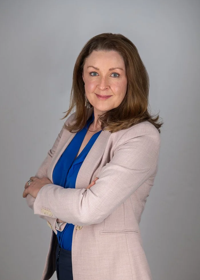 Susan Bradfield Photography headshot photo of a woman wearing a pink blazer and blue shirt