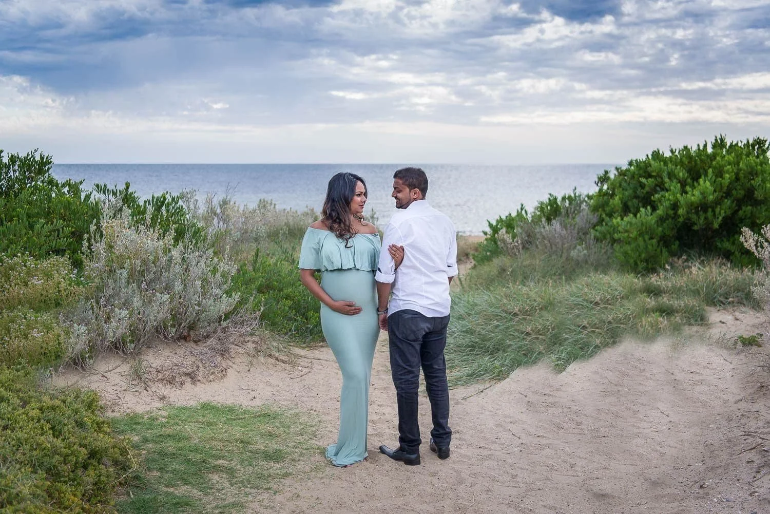 Susan+Bradfield+Photography+pregnant+woman+in+green+dress+arm+in+arm+with+partner+at+the+beach_compressed.jpg