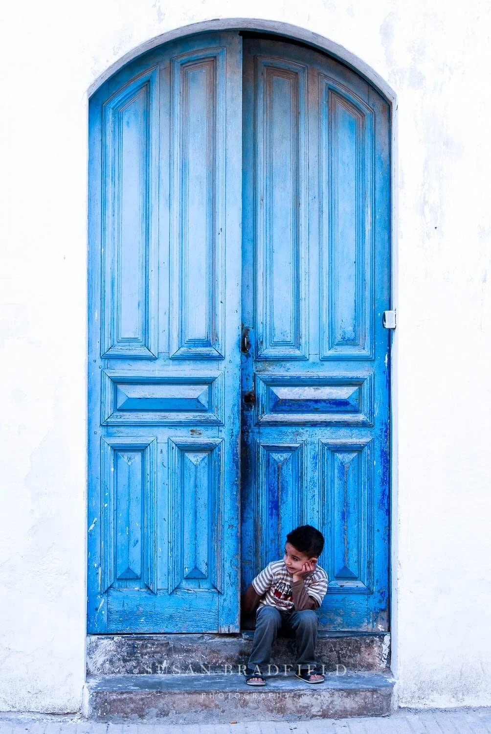 Susan+Bradfield+Photography%2C+boy+sitting+in+front+of+blue+door+in+Morocco.jpeg_compressed.jpg