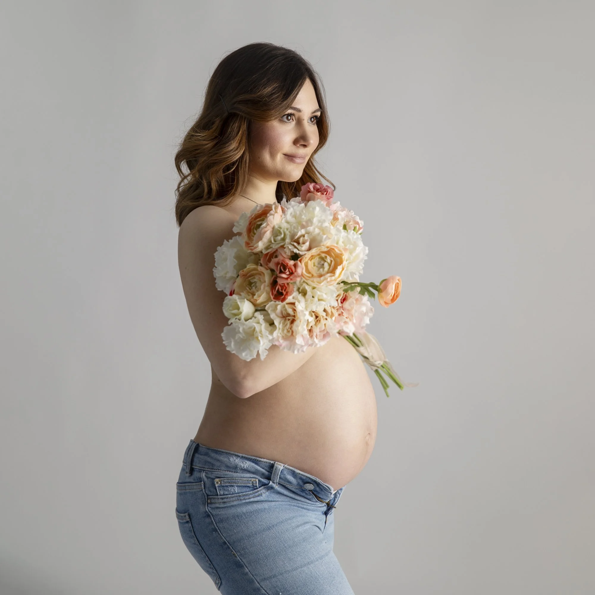 Werdende Muttereinem Blumenstrauss während eines Babybauchfotoshootings. Modeorientierte und elegante Schwangerschaftsfotografie in NRW