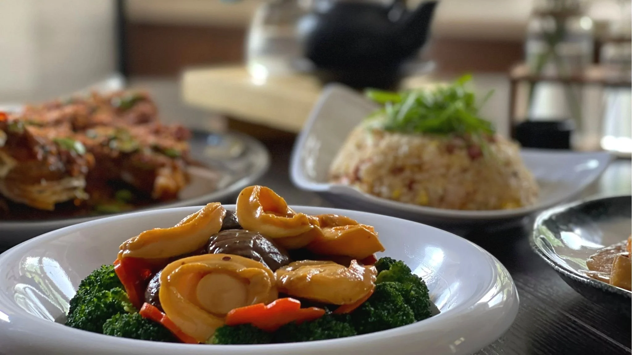 Asian cuisine with abalone, broccoli, and rice on a table.