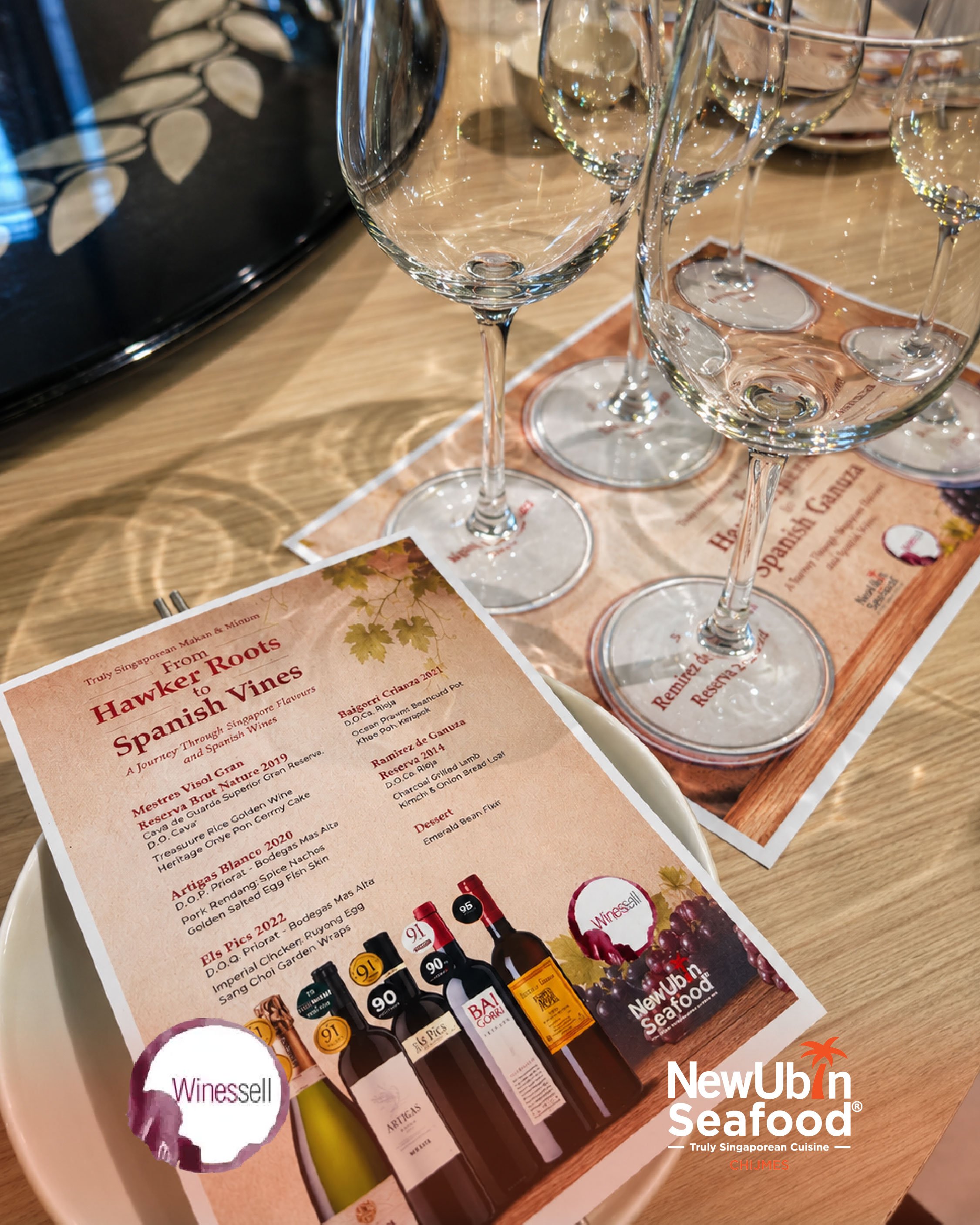 A menu on a table at a restaurant called NewUbin Seafood, featuring wine bottles and a flyer for a wine and Spanish wine tasting event, with empty wine glasses in the background.