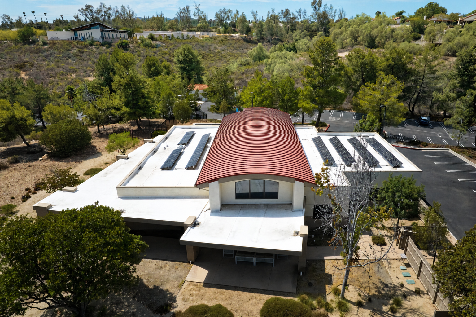 Aerial view of curved red-roof rectory.png
