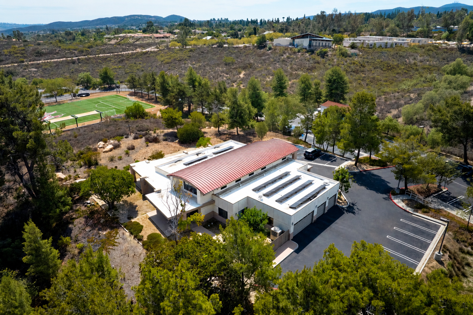 Red-roof rectory amid wooded hills.png
