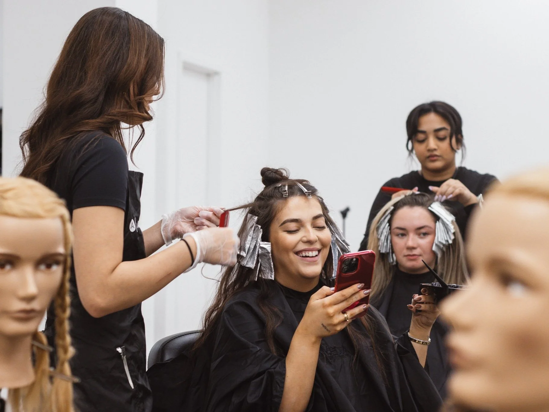 Guest smiling while a student works on their hair during a hands-on salon training session