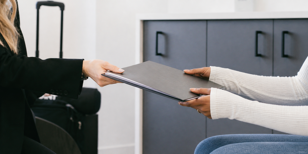 Admissions team member handing a folder to a prospective student, representing support and information for the financial aid page.