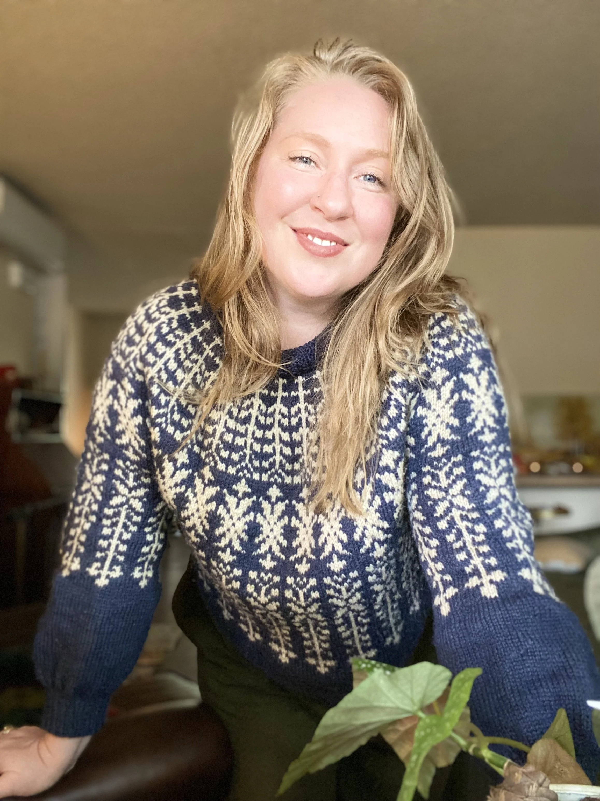 Photo of a smiling white woman with blonde hair, blue eyes wearing a blue and white sweater.
