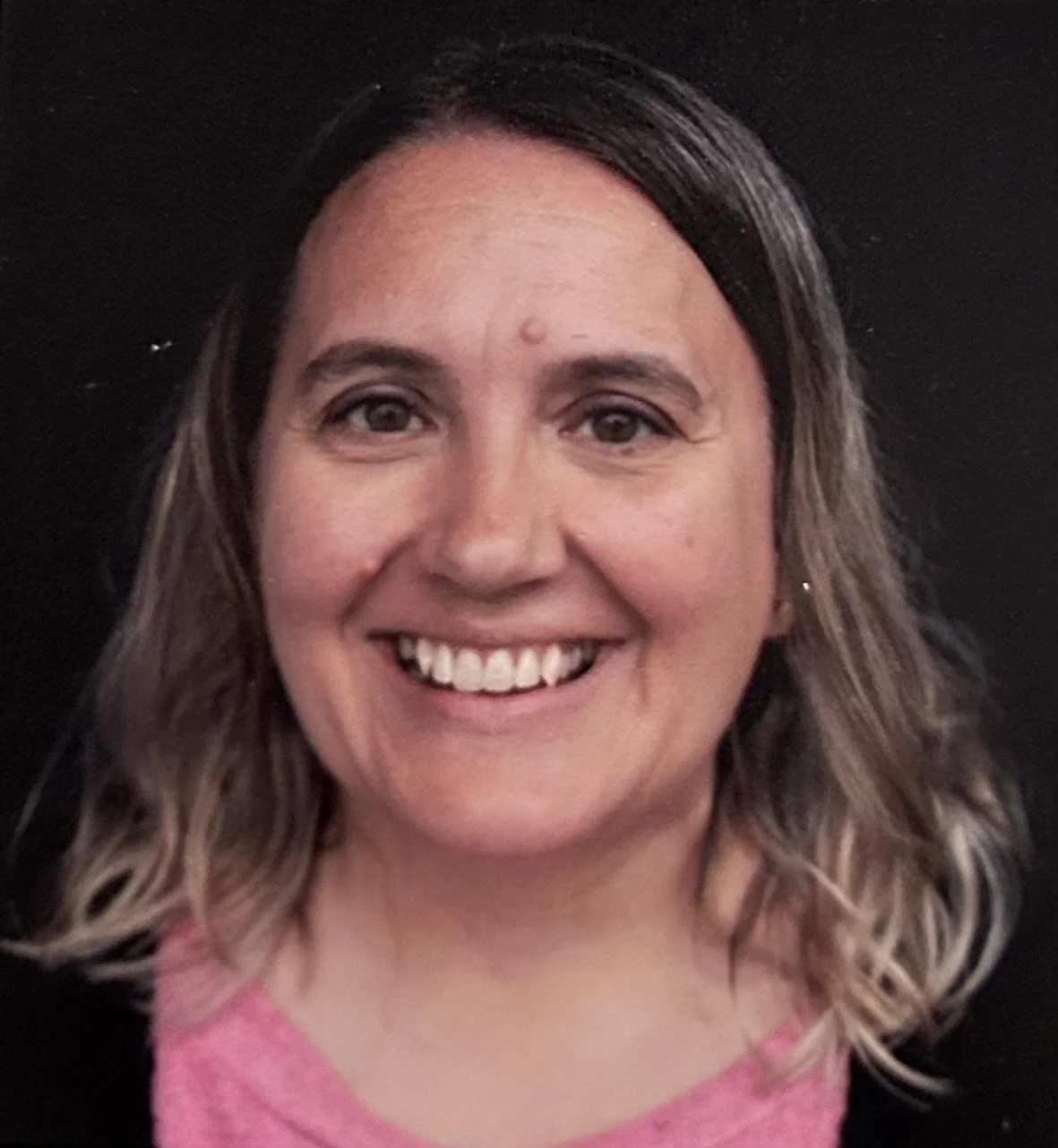 Picture of Nancy Weier who has shoulder length brown hair with blonde highlights. Nancy has a big smile is is wearing a pink shirt with a black cardigan.