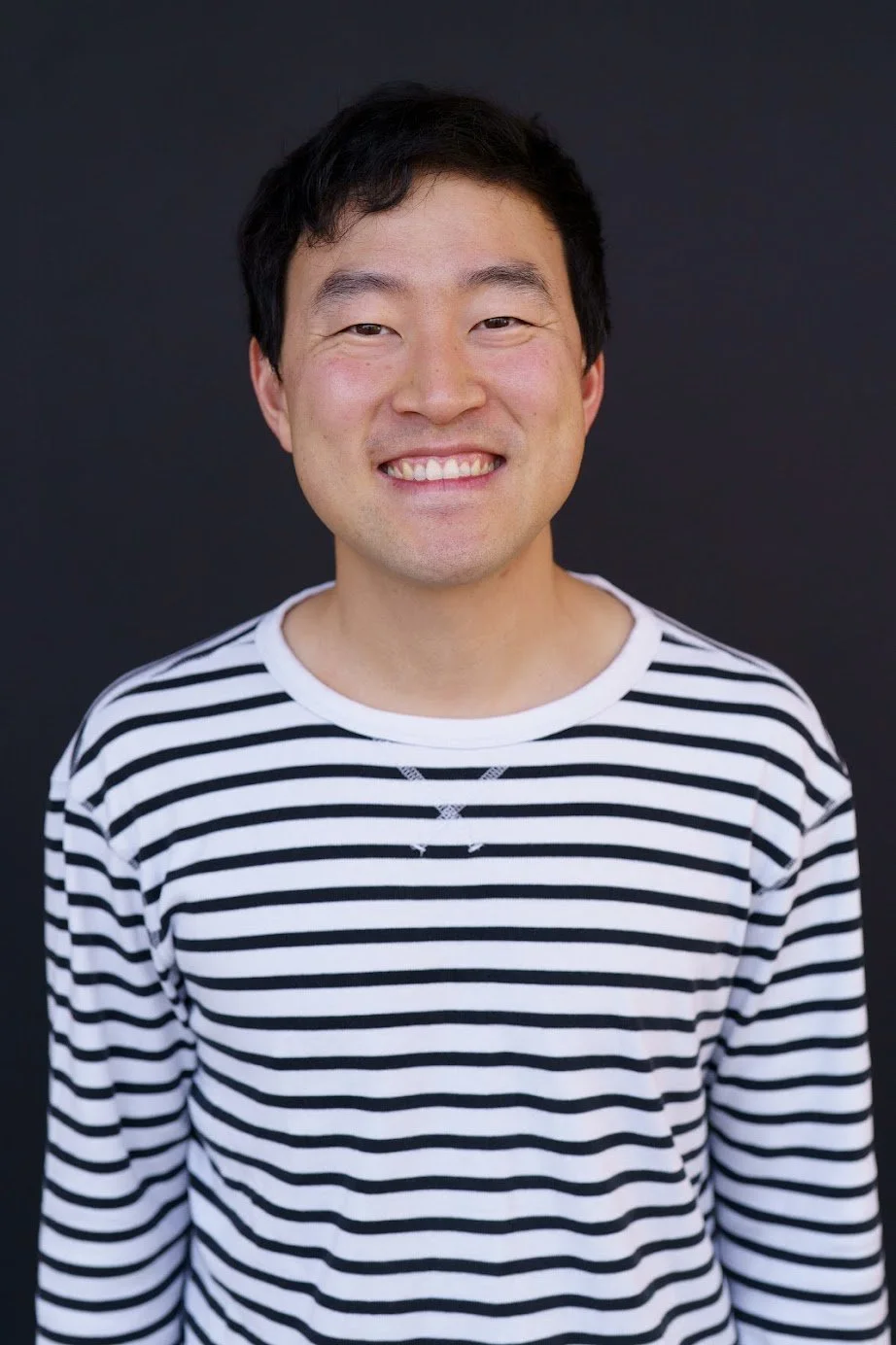 Picture of Facilities Officer, Wonho, who has short dark hair, a friendly smile, and is wearing a black and white striped long sleeve shirt.
