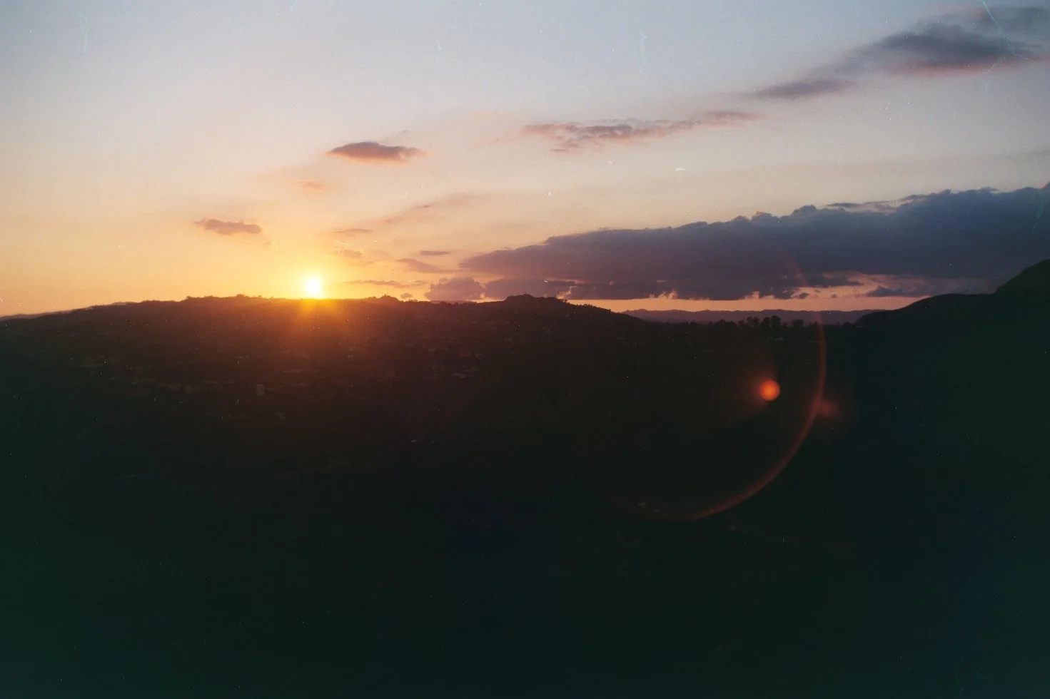 Sunset over a hilly landscape with clouds in the sky