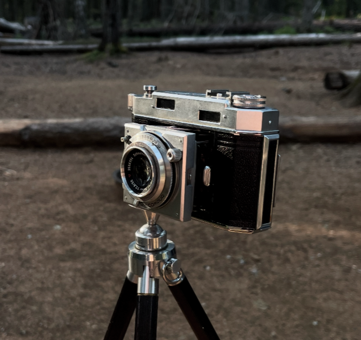 Agfa Karat 36 film camera mounted on a tripod outdoors in a wooded area.