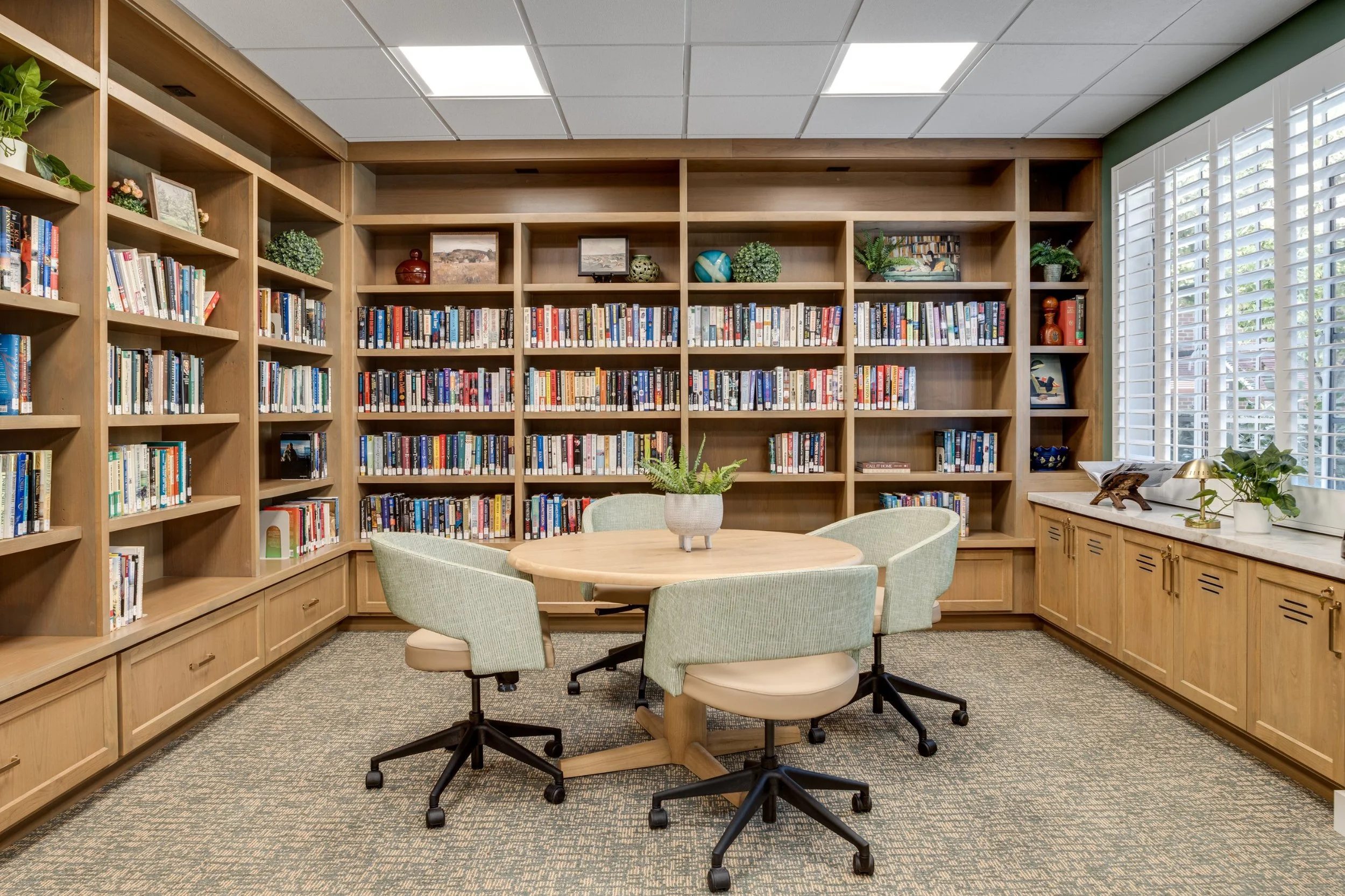 Library with built-in wood shelving at Claremont Manor senior living community, photographed by a Los Angeles interior photographer