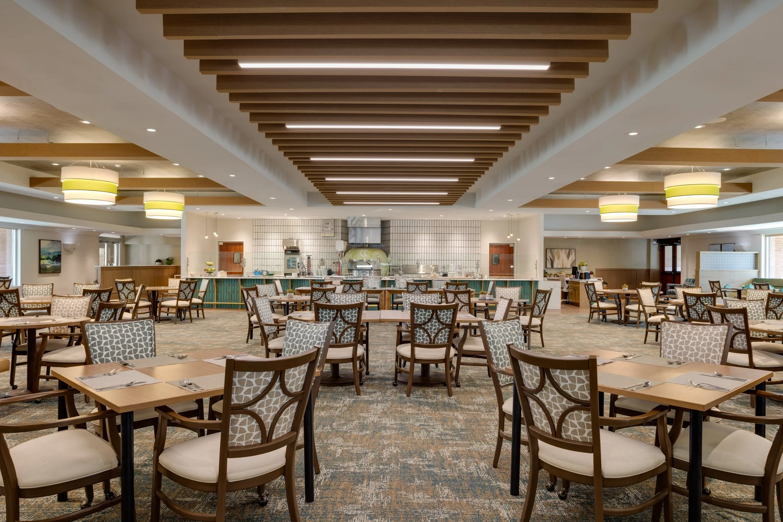 Senior living dining room with an exhibition kitchen and pizza oven at Claremont Manor, shot by a Los Angeles interior photographer
