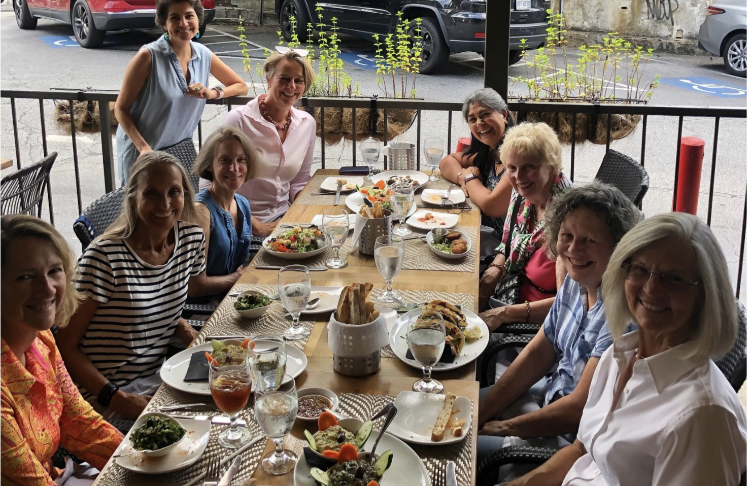 A group of twelve women enjoying a meal at an outdoor restaurant. This is from group that meets for lunch.