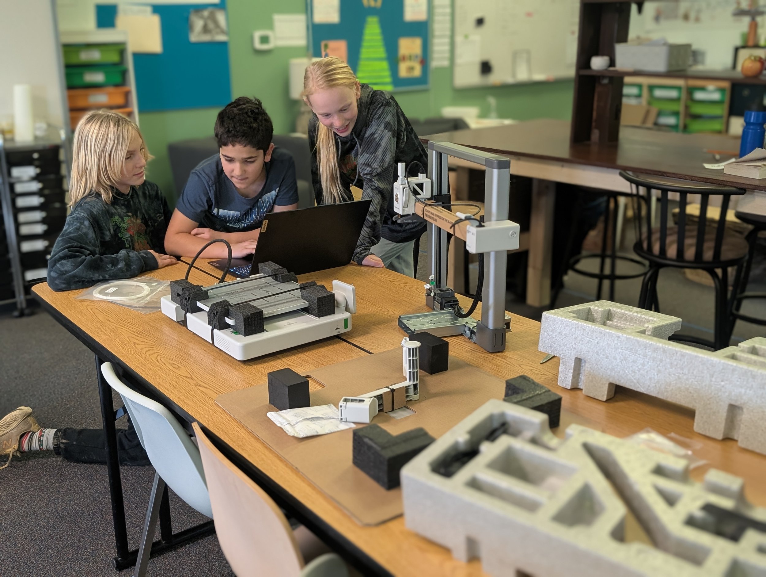 Learners collaborating around a laptop and project materials