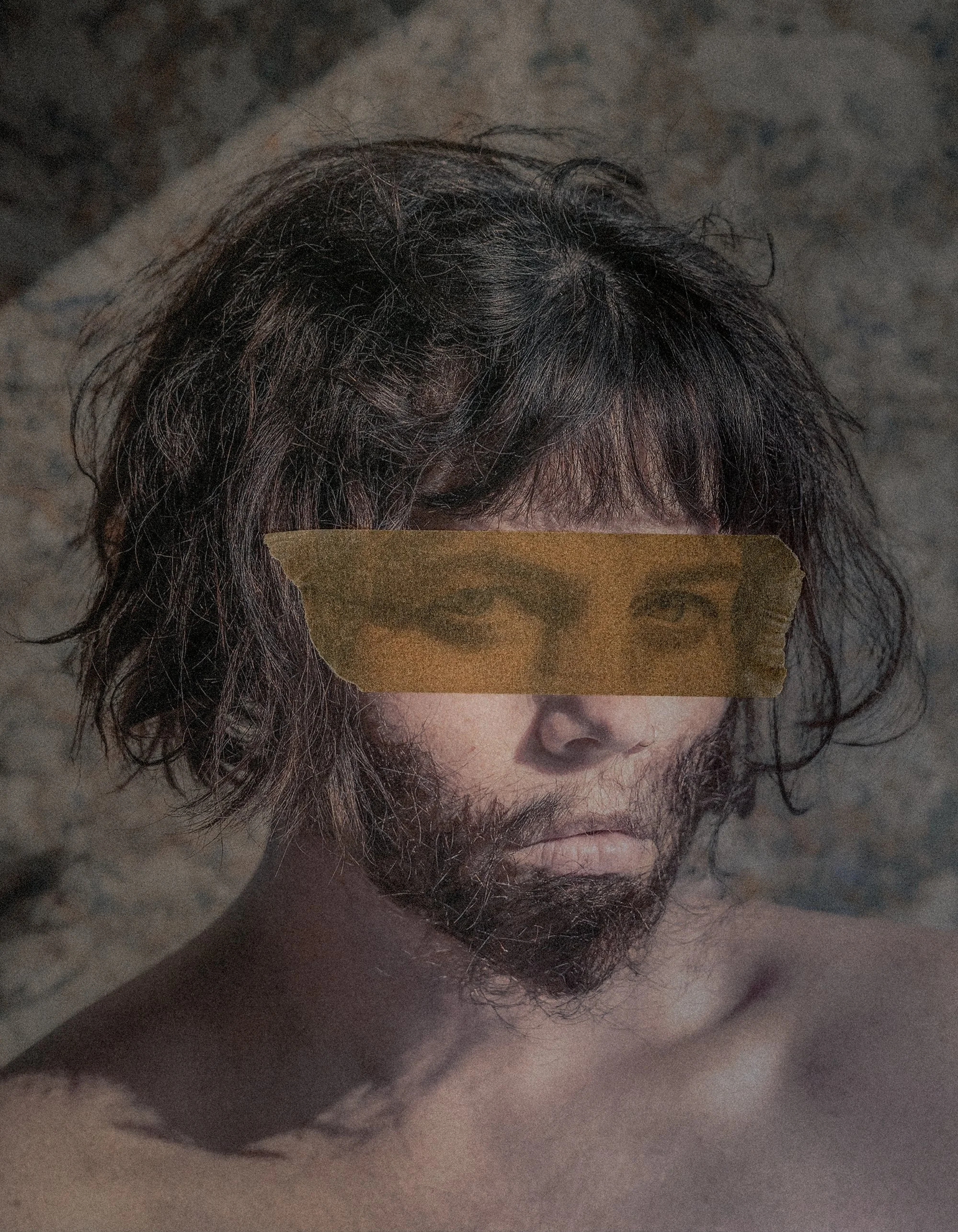 A portrait of a person with messy, curly hair and a beard, with their eyes obscured by a strip of torn brown paper with a printed image of eyes.