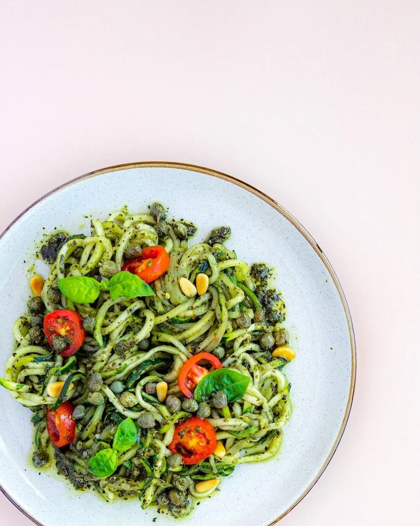 Vegheadsto vegan kaliscious pesto with pasta on a plate with pink background