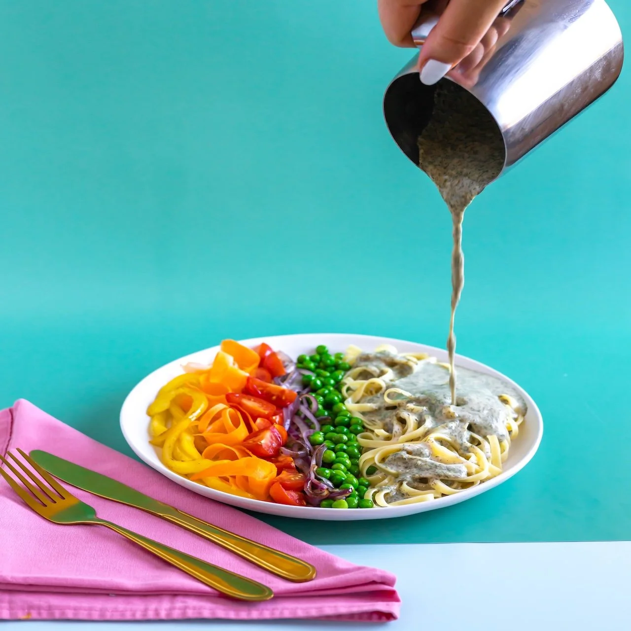 Vegheadsto Vegan Alfredo sauce  being poured on a pasta plate