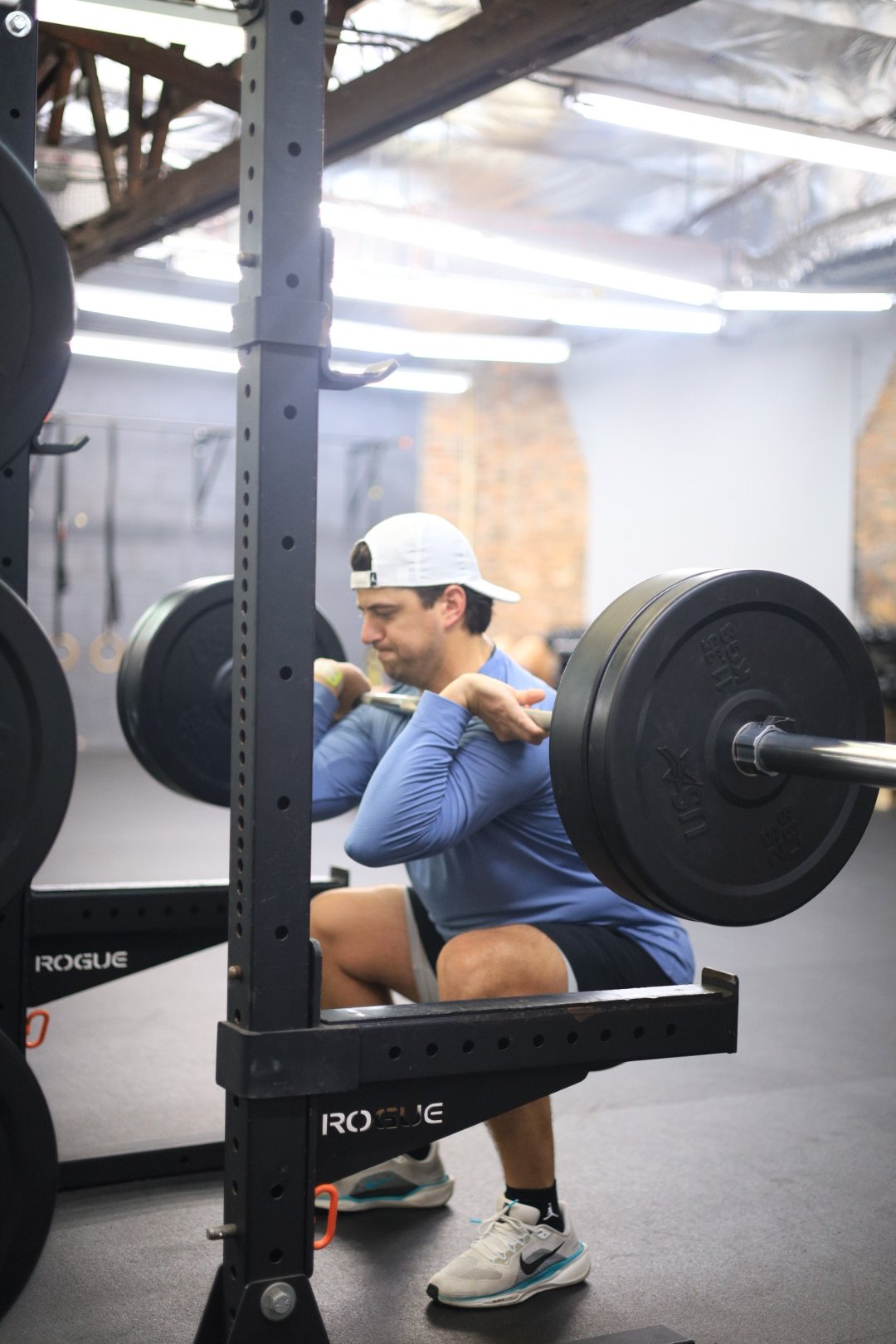 Coach teaching proper front squat technique during semi-private strength training at Perform24 in Tampa