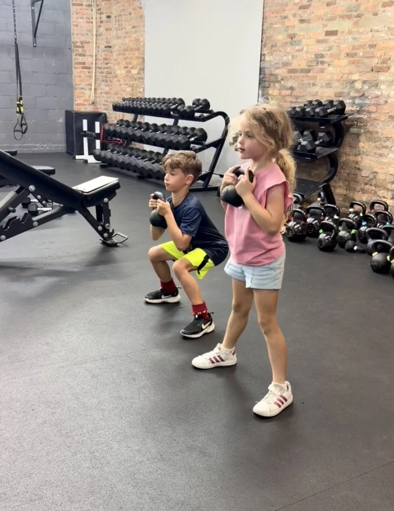 Two young athletes performing goblet squats at Perform24 in Tampa, Florida as part of youth athletic development training.