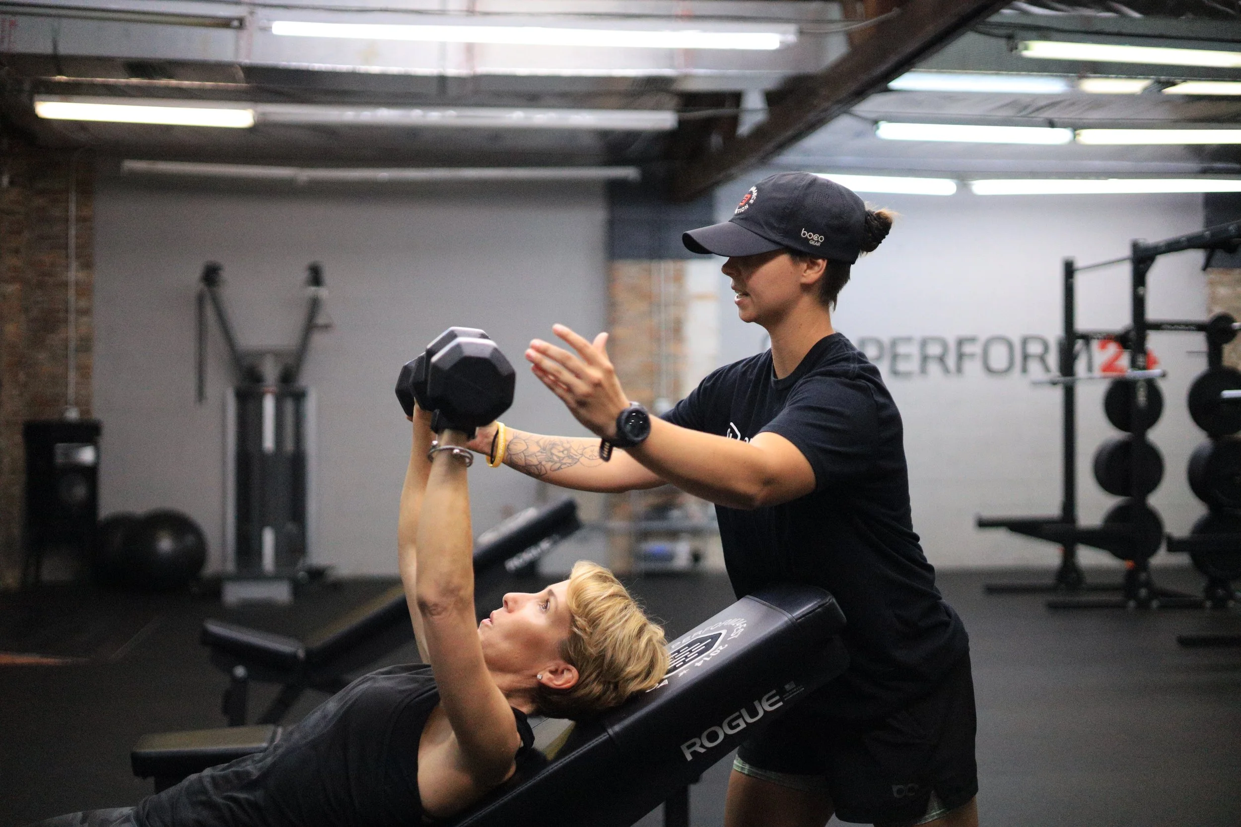 Strength coach providing hands-on instruction during a training session at Perform24 strength and performance gym in Tampa Florida